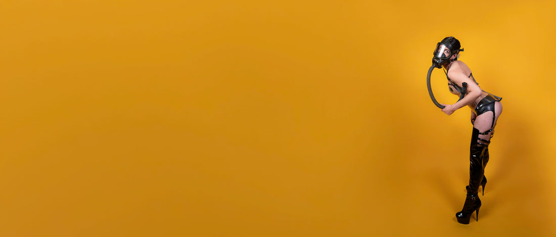 Femme person står med gasmaske og lårlange støvler - skubber måsen bagud på en indbydende måde